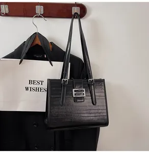 Detail of black textured tote bag featuring glossy finish and silver buckle on wood hook