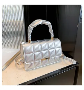 Détail du sac argenté matelassé avec fermoir doré et poignée froncée élégante