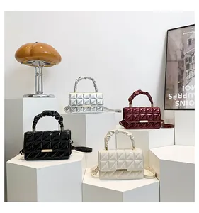 Sacs à main en cuir verni matelassé en quatre couleurs sur des socles géométriques