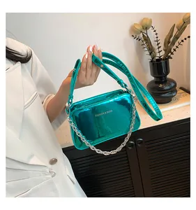 Detail of teal metallic square bag with silver chain strap and fashion lettering