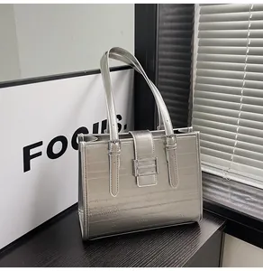 Detail view of the silver metallic textured surface and silver buckle of the tote bag