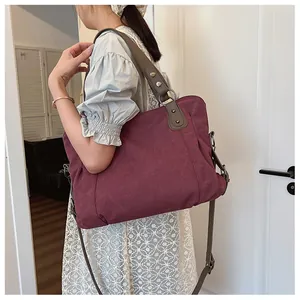 Détail d'un sac cabas en toile bordeaux avec bandoulières renforcées et rivets en métal