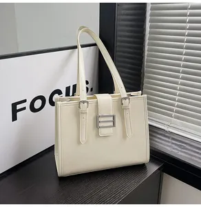 Detail of a creamy white tote bag featuring fine horizontal texture and silver buckle