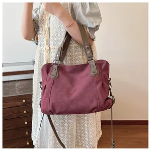 Détail du grand sac cabas en toile bordeaux porté par un mannequin dans un décor naturel