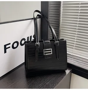 Detail of black textured tote bag featuring horizontal stripes and silver metal buckle