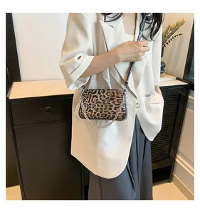 Close-up of leopard print crossbody bag with silver chain strap on a model indoors