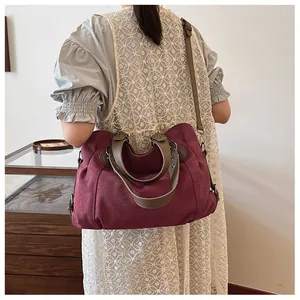 Grand sac cabas bordeaux avec poignées marron, porté sur une robe en dentelle blanche