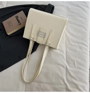 Detail of cream leather tote bag with silver buckle and adjustable shoulder strap