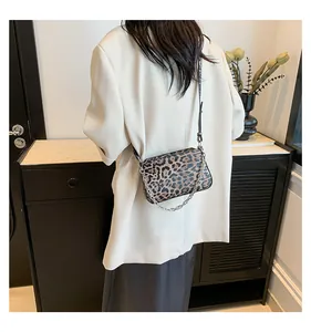 Detail of leopard print crossbody bag with silver chain strap on a white blazer