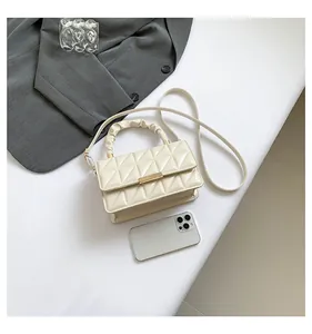 Détail d'un sac à main en cuir verni matelassé crème avec poignée froncée et fermoir doré