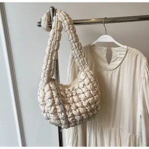 Close-up of beige ruched cloud bag with sparkling rhinestone tassel and soft texture