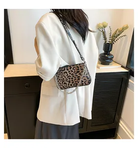 Detail of trendy leopard print baguette bag with silver chain strap on a white blazer