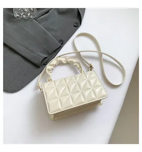 Détail du sac en cuir verni blanc crème avec motif matelassé et poignée froncée