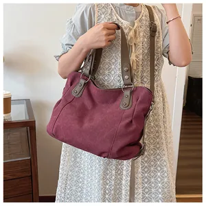 Détail du sac cabas en toile bordeaux avec anses en similicuir marron et rivets