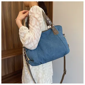 Sac cabas en toile bleue avec lanières en cuir marron porté pour montrer sa capacité