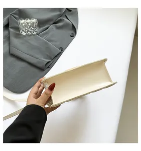 Détail de la petite sacoche carrée en cuir verni beige avec finition brillante