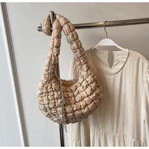 Beige pleated cloud bag featuring quilted texture and rhinestone tassel details