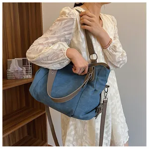 Détails des bandoulières en cuir marron et boucles en métal sur grand sac en toile