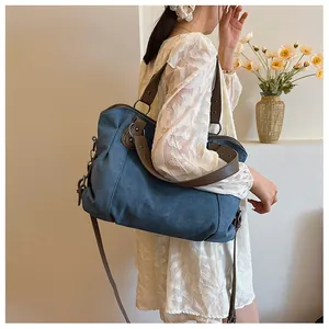 Détail du sac cabas en toile bleue avec poignées en cuir marron et rivets métalliques