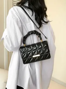 Sac bandoulière matelassé en cuir verni avec poignée plissée et boucle dorée sur modèle