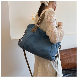 Détail du grand sac cabas en toile bleue avec bandoulière en cuir sur le mannequin