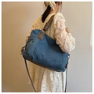 Détail du sac cabas en toile bleu vintage avec garniture en cuir et rivets sur mannequin