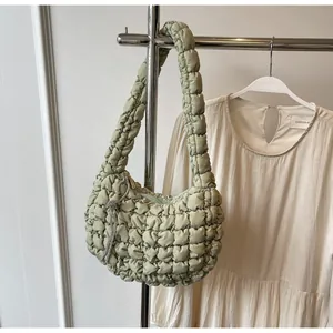 Detail of sage green quilted puff shoulder bag with silver rhinestone tassel charm