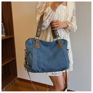 Détail du sac fourre-tout bleu foncé avec anses en cuir marron et rivets décoratifs