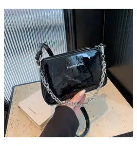 Detail of glossy black patent leather shoulder bag with silver chain and white text