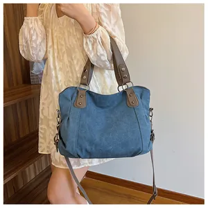 Détail du sac cabas en toile marine avec poignées en cuir marron et rivets vintage