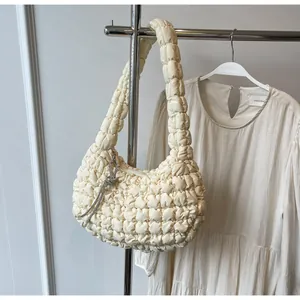 Detail of creamy quilted bubble bag featuring 3D puff texture and silver tassel zipper