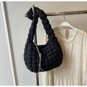 Close-up of black puffer shoulder bag with ruched texture and rhinestone tassel detail