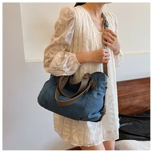 Détail d'un grand sac cabas en toile bleu foncé avec bandoulière réglable en cuir marron