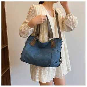 Détail du grand sac cabas en toile vintage avec poignées en cuir marron et boucles bronze