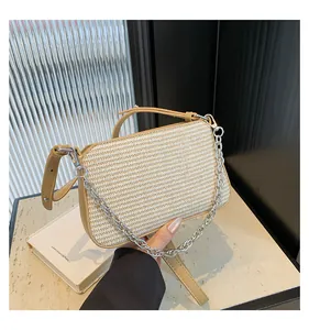 Detail shot of the woven straw texture and silver chain strap on the beige crossbody bag