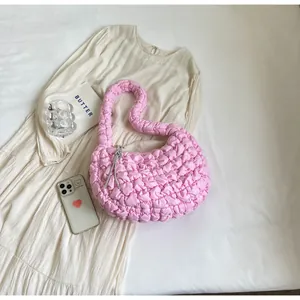 Pink bubble textured hobo bag detail with silver tassel on white pleated fabric