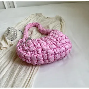 Detail of pink ruched cloud bag featuring quilted fabric and a silver rhinestone bow charm