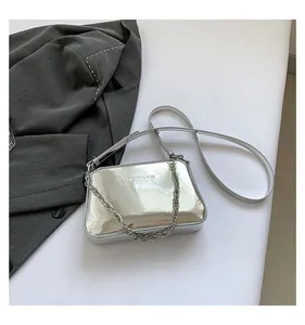 Detail of silver mirror PU leather handbag with metallic chain and fashion logo