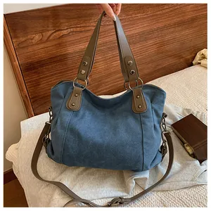 Détail du sac cabas en toile bleue avec poignées en cuir marron et boucles en métal