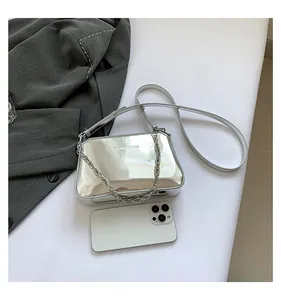 Flat lay of silver mirror surface bag with chain strap and fashion logo detailing