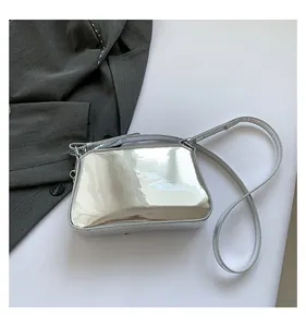 Close-up of silver mirror leather handbag with elegant metallic chain strap on white backdrop