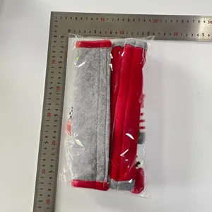 Detailed view of red and grey plush Christmas fridge handle covers with measuring tool