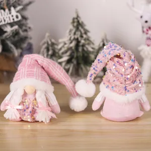 Pink Christmas gnome ornaments with sequins and knitted hats on a rustic wooden table