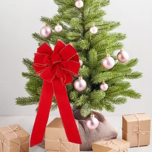 Red Christmas velvet bow with gold stitching on a decorated tree with gift box