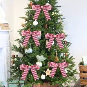 Five red and white striped Christmas bows decorating a tree in a cozy festive room