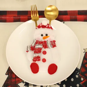 Detalle del porta cubiertos de muñeco de nieve con gorro y bufanda sobre un plato