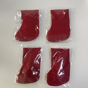 Set of four red burlap Christmas stockings individually wrapped in plastic on a white background