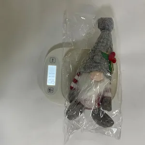 Detailweergave van een gebreide kerstkabouter die op een digitale weegschaal wordt gewogen
