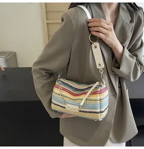 Detail of a rainbow striped cylinder straw bag with white leather strap on a model