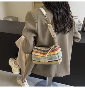 Detail of colorful woven cylinder bag featuring rainbow stripes and white leather strap